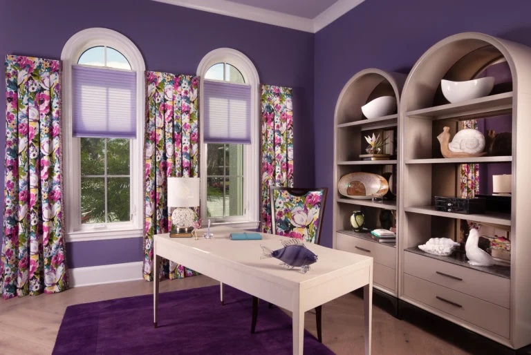Desk set up in a purple room with floral drapes