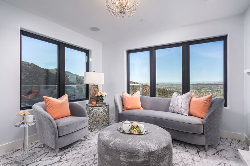 cool gray plush furniture with pastel orange pillows set against large windows overlooking dry valley in summer