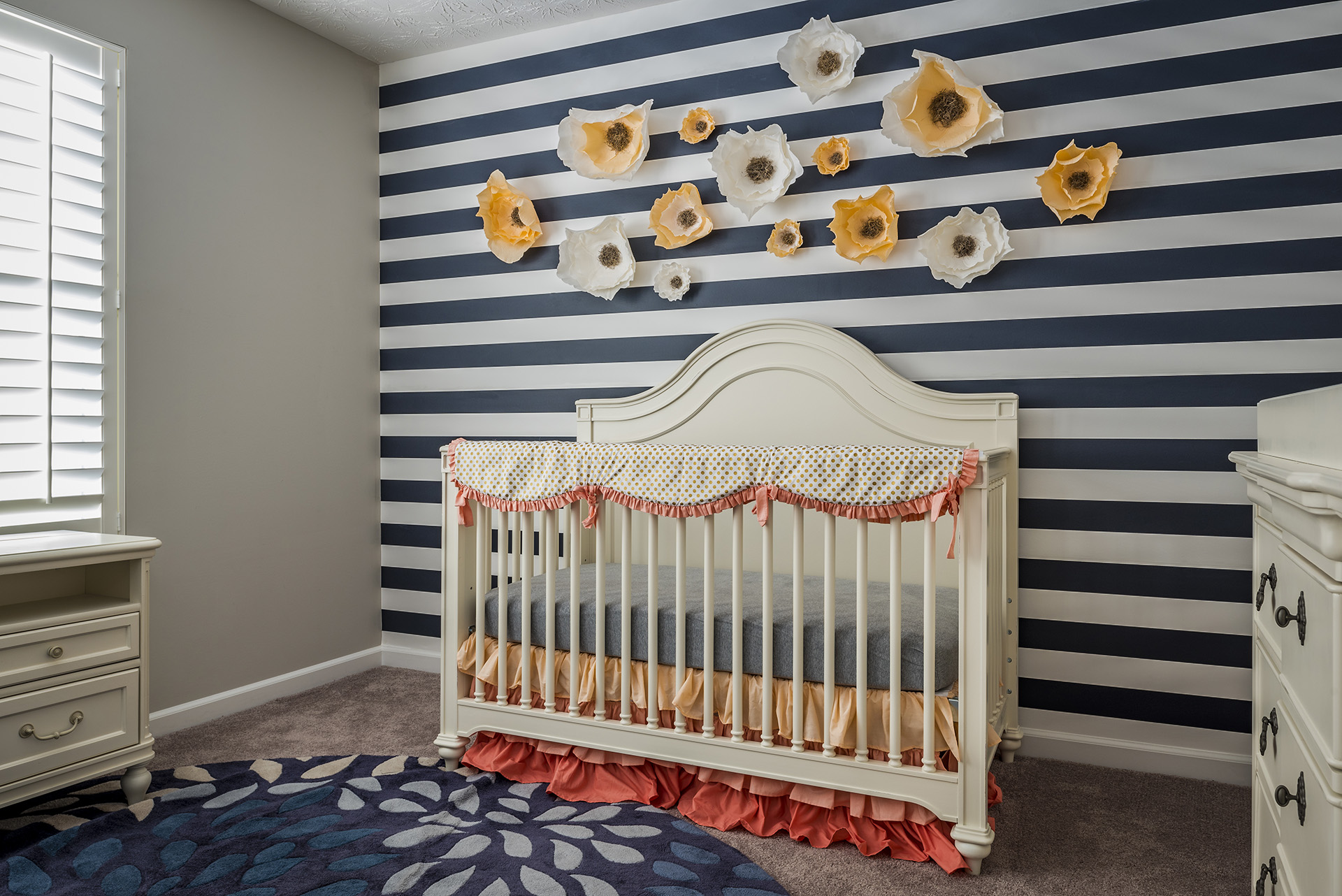 nursery bed in front of a wall decorated with flowers and striped decor