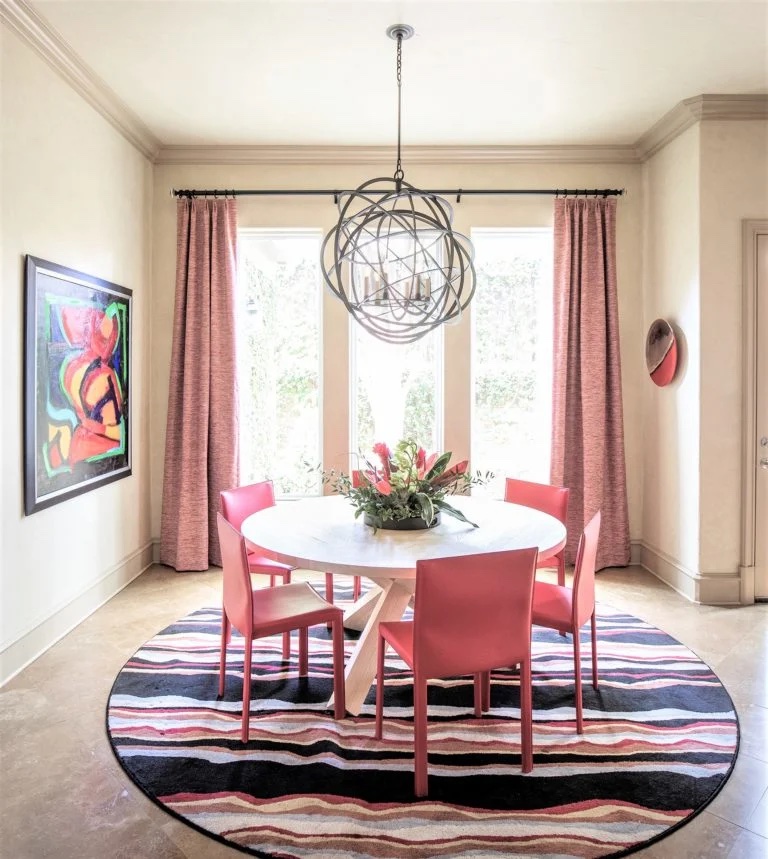 Dining table with pink chairs and a chandelier 