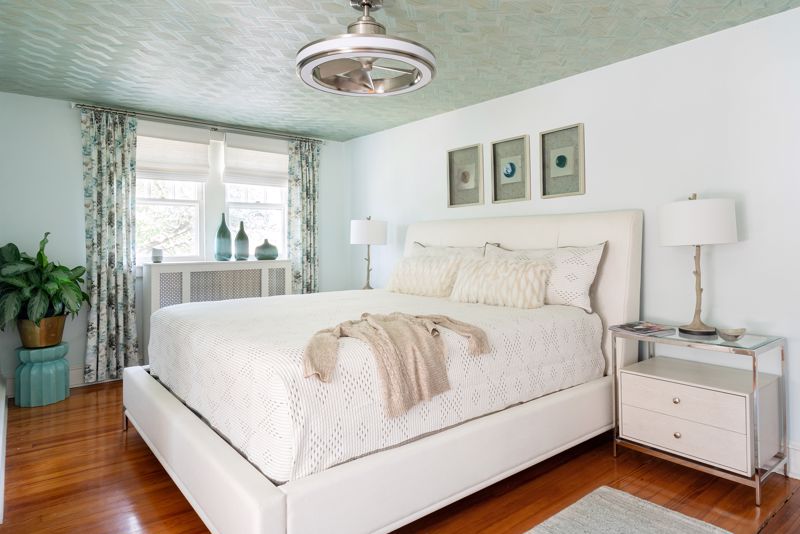 white bed on hardwood floor with pale green decorative ceiling