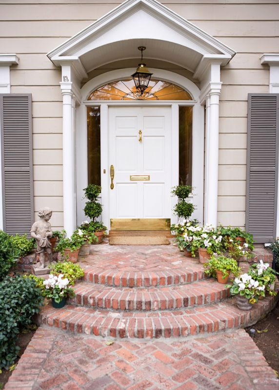 white front door in a classical style decorated with plants on the front steps