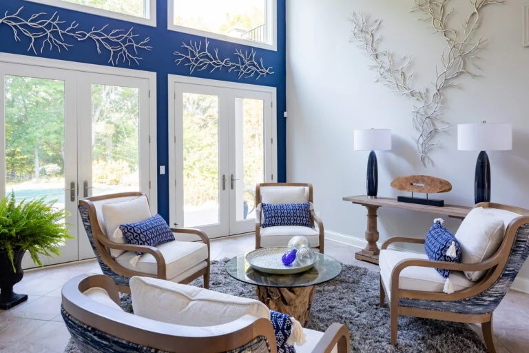four decorative white and brown chairs with blue cushions in a coastal style sun room