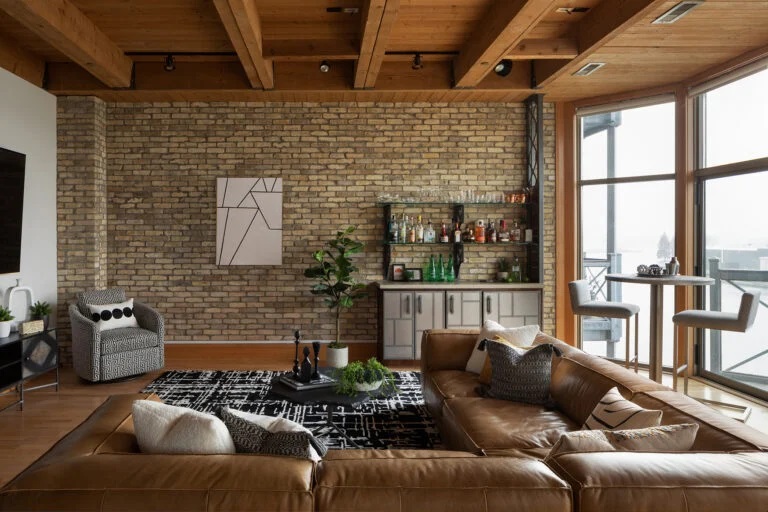 Brown couch set against brick wall in living room showcasing the industrial style interior design