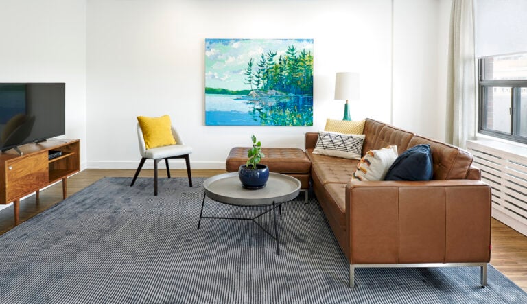 brown couch on gray rug with a blue painting showcasing the minimalist style interior design