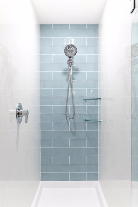 metal shower head set against a pale blue tiled wall in a shower stall