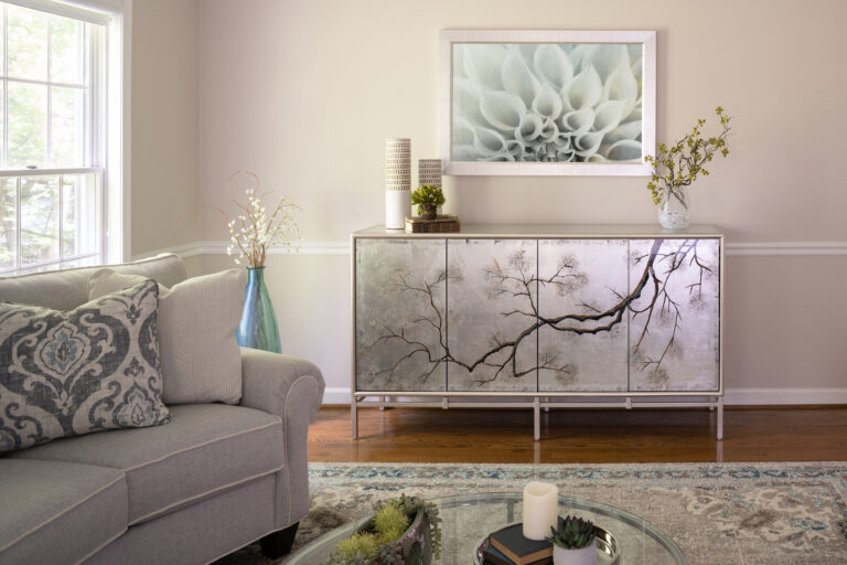 gray couch and glass coffee table on a decorative white rug in front of asian inspired cabinet showcasing natural elements