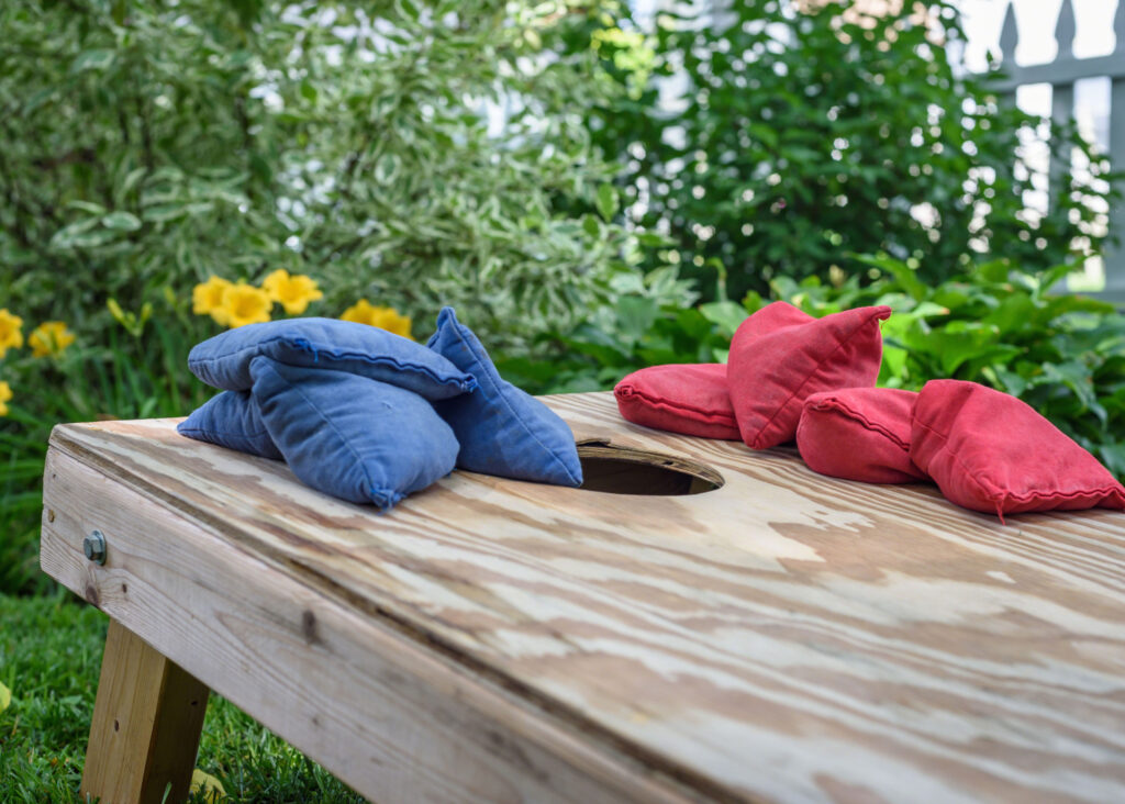 blue and red bean bags resting on wooden slide with hole for bean bag toss game
