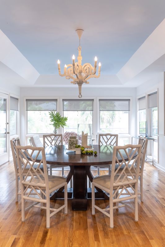 wooden round table on hardwood floors in coastal dining room with natural light