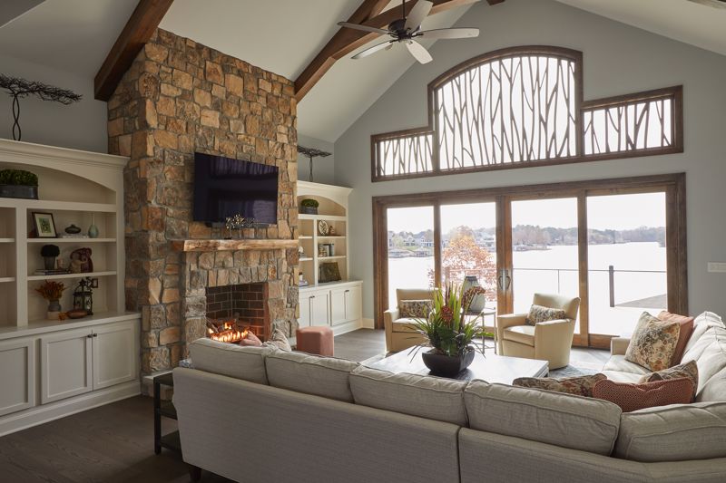 light gray couch set against natural stone chimney and large windows showcasing biophilic interior design in cincinnati