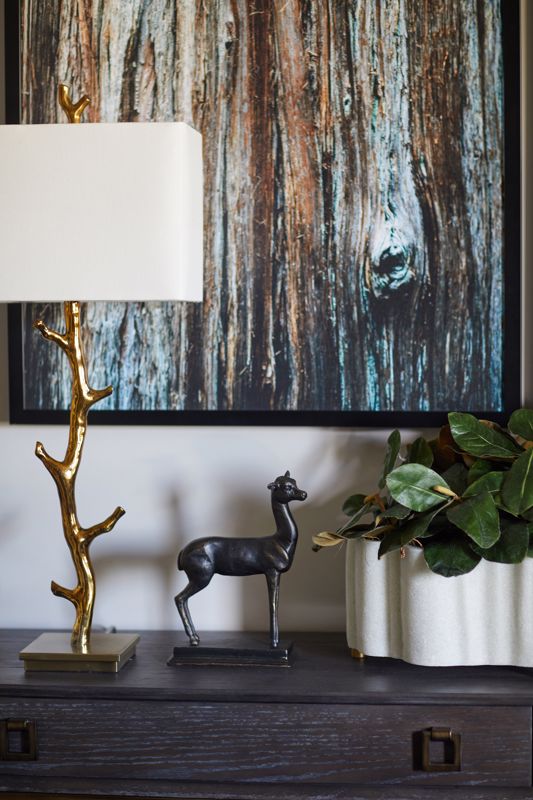 exotic animal figurine with gold-plated tree branch lamp set against bark texture print showcasing biophilic design