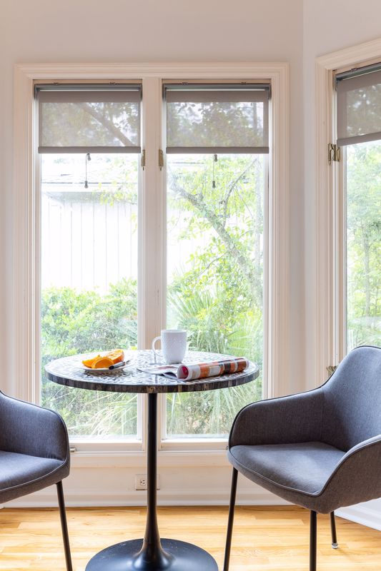 simple chairs and round table set against tall bay windows showcasing breakfast nook interior design in Cincinnati