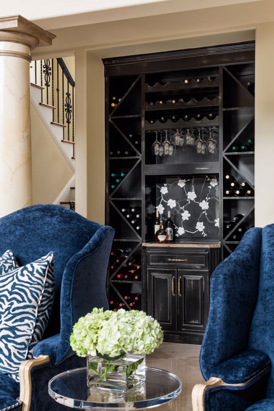 dark blue luxurious Victorian chairs set against decorative black wine cabinet in maximalist interior design OH