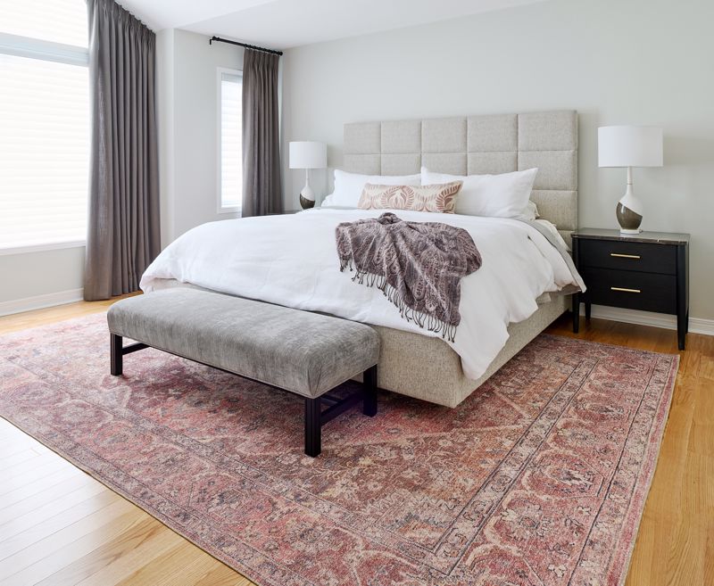 pink decorative print rug underneath modern white bed showcasing best modern vintage interior design in Cincinnati OH