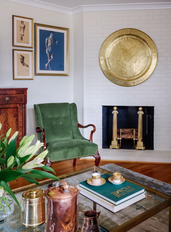 best vintage and contemporary interior decorating in Cincinnati OH, green chair on hardwood flooring set against white wall with art and gold decor